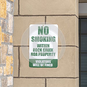 Square No Smoking sign on the exterior stone wall of apartment in Rock Creek Utah