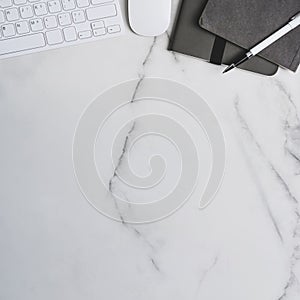 Workspace with keyboard notebook, mouse and copy space on marble table.