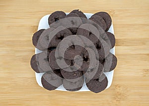 square plate with round chocolate donuts on a light wood table