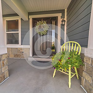 Square Porch and facade of home decorated with colorful flowers and wreath on the door