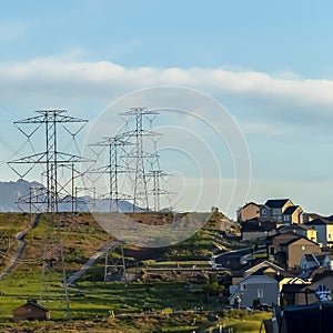 Square Power lines towering over neighborhood and roads in the valley on a sunny day