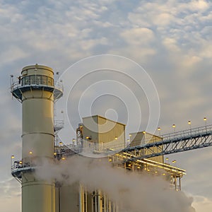 Square Power Plant in Utah Valley emitting smoke against sky filled with puffy clouds