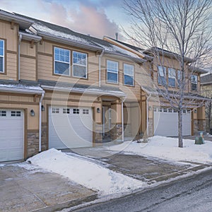 Square Puffy clouds at sunset Townhouses exterior with attached garage and a driveway cleared