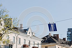 Square road sign with a white arrow on a blue sky background. Indicates straight ahead