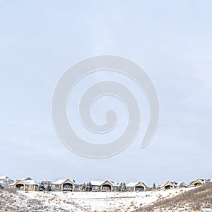 Square Scenic winter landscape of homes sitting on top of hills dusted with snow