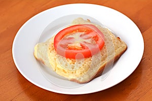 Square shape buttered English crumpet with slice of tomato