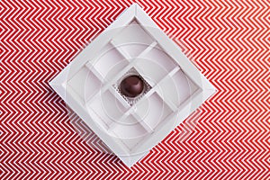 Square-shaped chocolate box with one single candy.