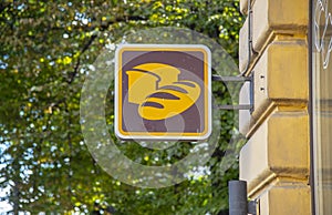 A square sign with bread painted on it hangs on the corner of the building