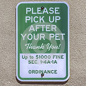 Square Sign that reads Please Pick Up After Your Pet against a concrete wall surface