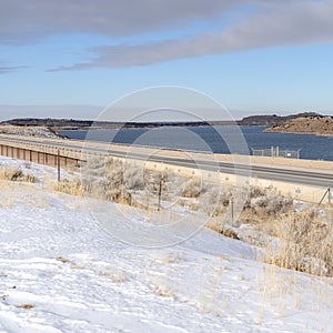 Square Snow covered terrain along a road overlooking mountain and lake in winter