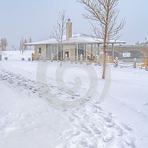 Square Snowy trail along Oquirrh Lake with view of a clubhouse and arched bridge