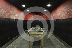 A square space with black and red defaced walls with space for a football in a nightclub