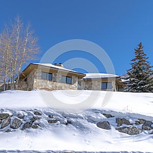 Square Stone home with snowy hip roof on a hill in Park City Utah viewed in winter