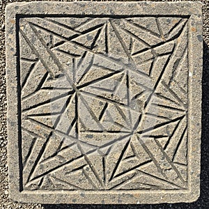 Square stone tile with engraved geometric pattern