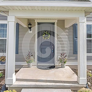 Square Symmetrical house facade with vinyl wood siding and gray front door