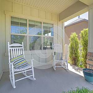 Square Two white rocking chairs with striped pillows on a porch of a house