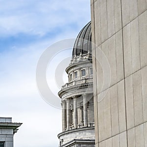 Square Utah State Capital building and dome viewed behind a stone building exterior