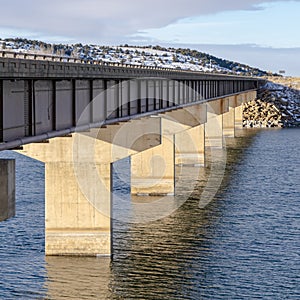 Square View of the abutments underneath a beam bridge supporting the deck over lake