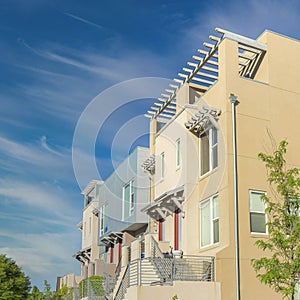 Square Whispy white clouds Fenced residential buildings with stairs to the verandas at Dayb