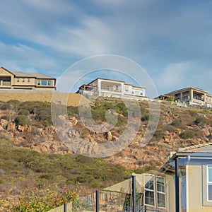 Square Whispy white clouds Uphill residential houses with glass fence surrounding the Doubl