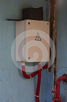 A square white box with an electrical panel on the wall of a building.