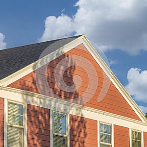 Square White puffy clouds House exterior with rustic vinyl wood siding and chimney post wi