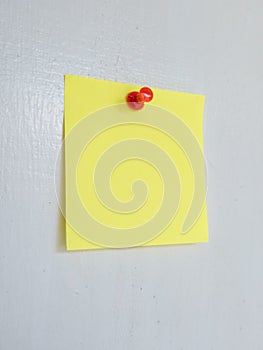 Yellow Post-it Note with Red Push Pin on a White Surface
