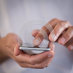 Squared image of young caucasian man using apps on a touchscreen smartphone