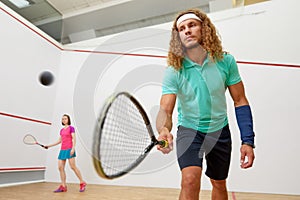 Squash male player with racket playing game with female friend