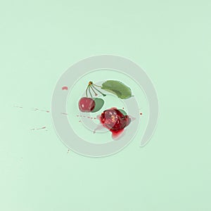 Squashed red cherry berry fruit on pastel green background. Summe red ripe juicy fruit concept