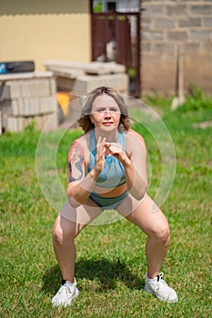 Squat exercises. girl plays sports in garden. fitness after childbirth