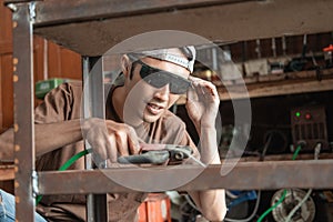 Squat male welder holding electric welder to weld iron frame