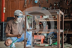 Squat welder prepares the equipment to make iron racks