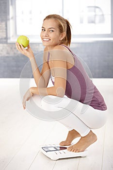 Squatter girl on scale holding apple