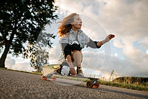 Squatting elegance. Girl exhibits grace in longboard riding, viewed below.