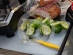 Squeezed lime, shot glass and knife sitting on small cutting board, making margaritas for party