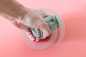 Squeezed money on woman fist. woman hand taking a roll of dollars