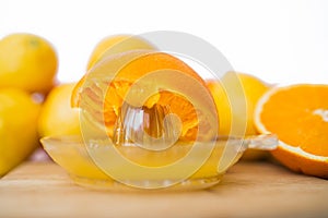 Squeezes fresh oranges with a juicer. Orange juice in a glass close to half of sliced â€‹â€‹oranges on a white background.