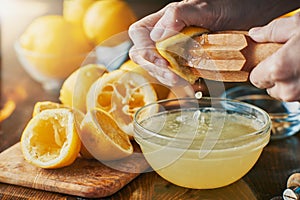 Squeezing fresh lemon juice with wooden reamer into bowl photo