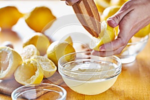 Squeezing fresh lemon juice with wooden reamer into bowl