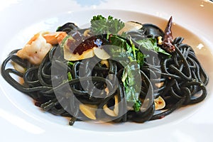 Squid Ink spaghetti with garlic, chilli and seafood that was placed on the white plate. This is a fusion of Thai and Italian