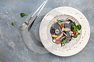 Squid ink spaghetti with seafood octopus, mussels and shrimps on light background. banner, menu, recipe place for text, top view