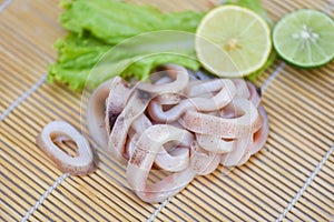 Squid rings on wooden plate, Fresh raw squid for cooked with lettuce vegetable salad and lemon lime