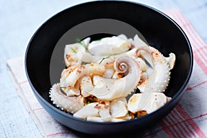 Squid salad bowl with herbs and spices sauce seafood on dining table - Tentacles octopus cooked appetizer food cooked in the