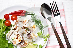 Squid salad with lemon herbs and spices on dining table top view / Tentacles octopus cooked appetizer food hot and spicy chilli