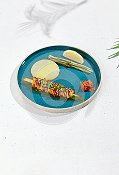 Squid yakitori in ceramic dish on white background. Japanese skewered squid with wasabi sauce. Grilled kalmar on bamboo skewer in
