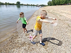 Sremska Mitrovica, Serbia, May 30, 2020 A boy and a girl are playing on the beach. Children play with water, sand and pebbles