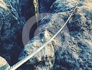 Srew with steel rope anchored into rocky wall