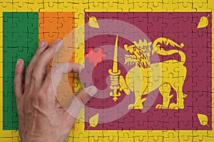 Sri Lanka flag is depicted on a puzzle, which the man`s hand completes to fold