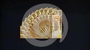 5000 Sri Lankan rupee notes stack on a black background. making a quarter circle, yellow golden color bills